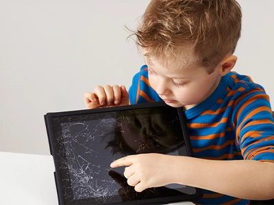 Little boy looking at cracked tablet screen