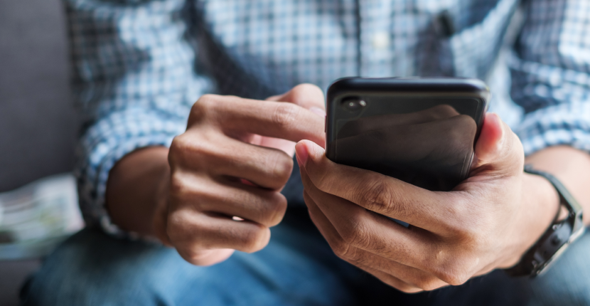 Person wearing blue plaid shirt scrolling on a black phone