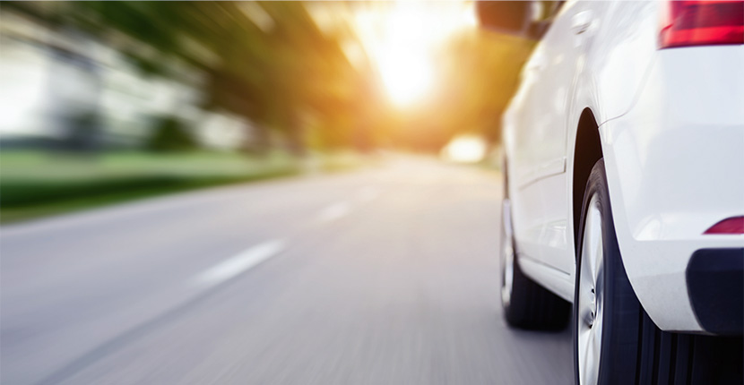 White car driving toward the sun