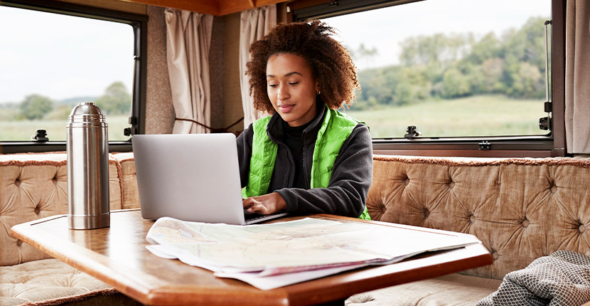 Woman wearing a green vest working on a laptop in a booth