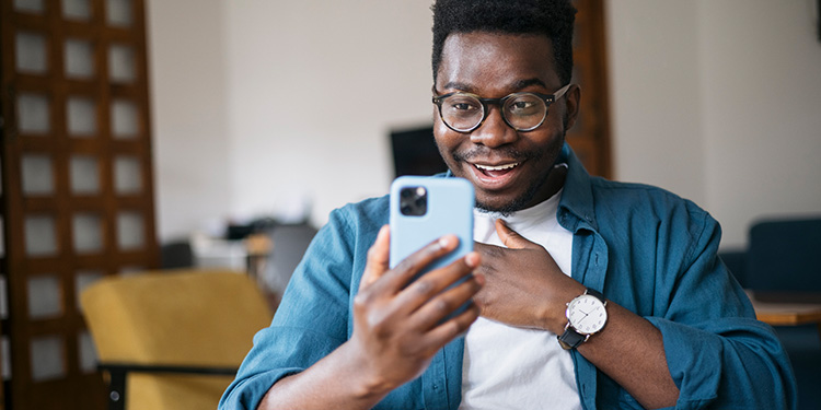 Man sitting in a chair looking excited at his cell phone