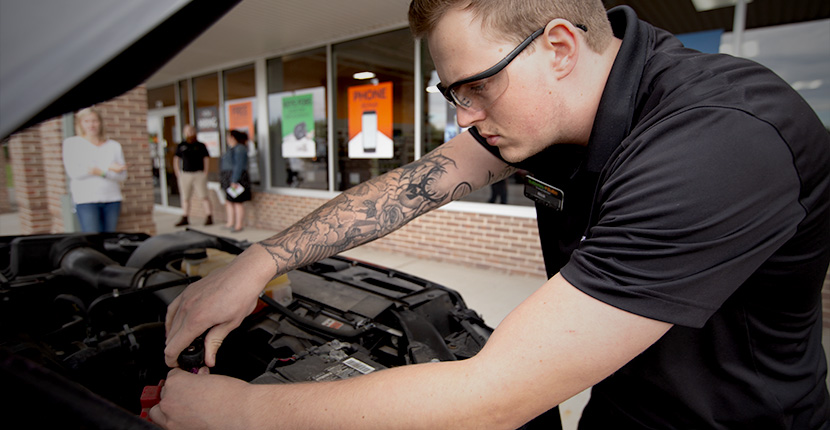 Worker installing a battery into a vehicle