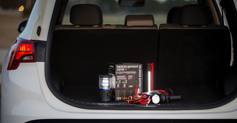 Charger, flashlights and jumper cables in the truck of a car