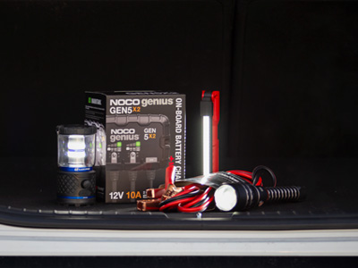 Charger, flashlights and jumper cables in the truck of a car