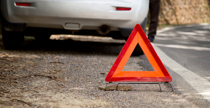 Car on the side of the road with a hazard cone