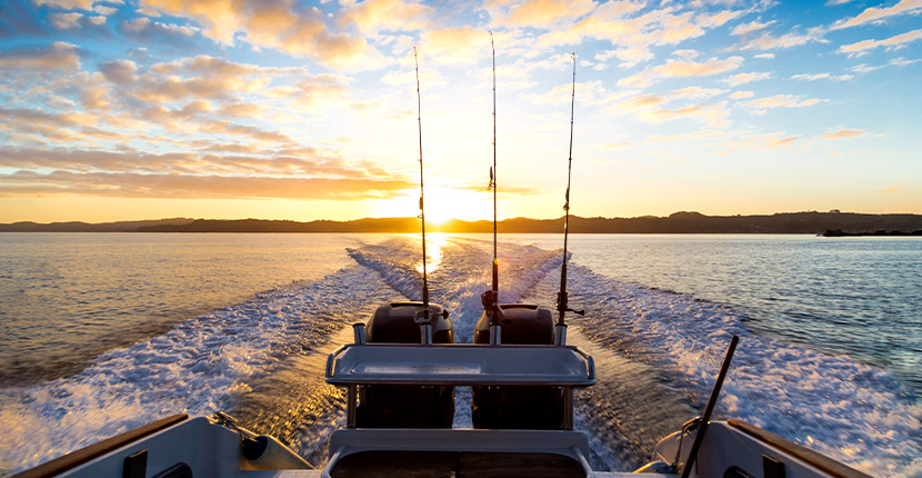 Boat on the water going away from the setting sun