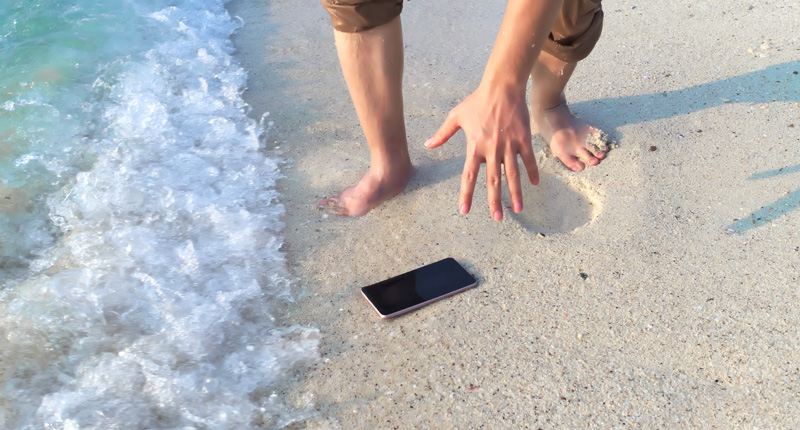 Picking up a phone that fell on the sand near the water