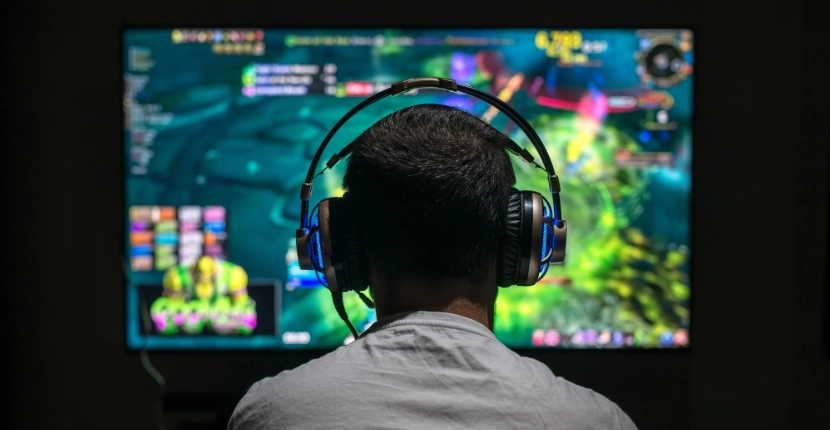 Someone with headphones on playing a game on a screen