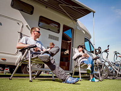 People sitting in lawn chairs outside an RV