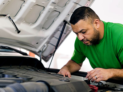 Man in green shirt looking at car battery