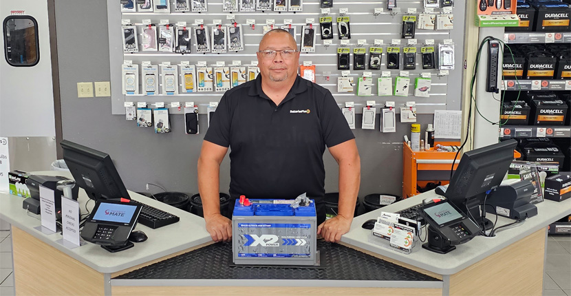 Store employee standing behind the checkout counter with an X2Power battery