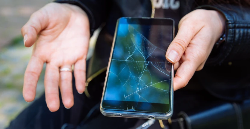 Holding a phone with cracked screen