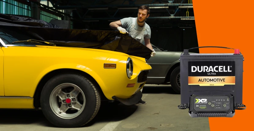 A guy putting a cover on a classic car, hero shots of a battery and charger