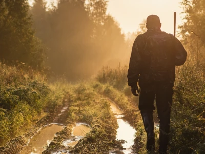 A hunter walking down a muddy path