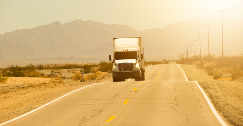 Semi truck driving down a road in extreme heat