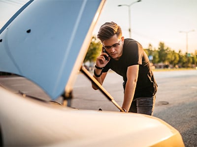 Guy on the phone looking inside car hood