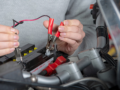 man connecting clamps to battery terminals