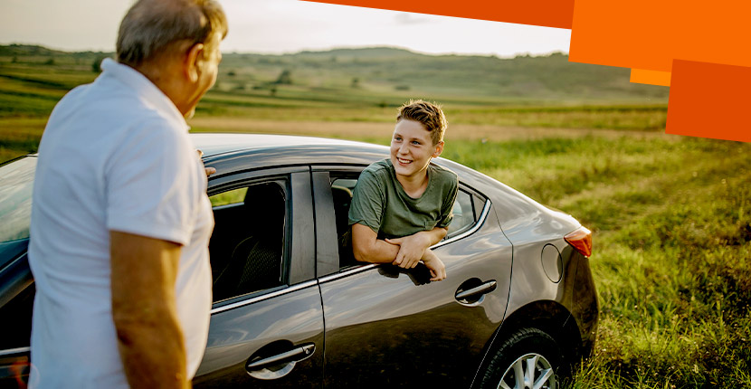 Kid hanging out of rear window of a car talking to older man