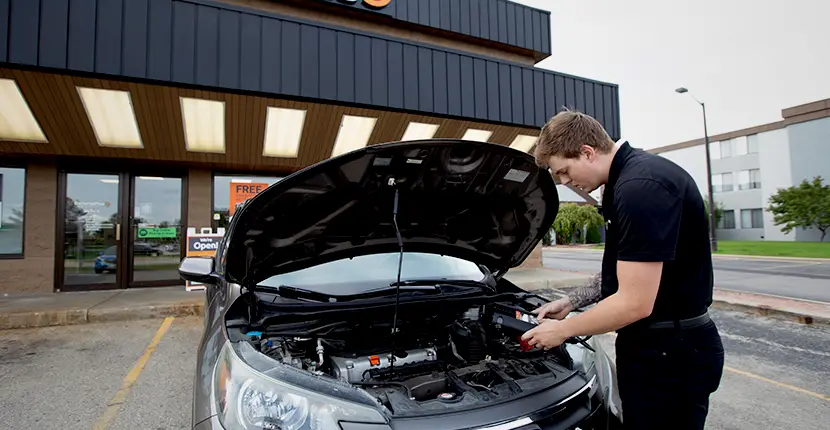 Worker checking a battery in a vehicle