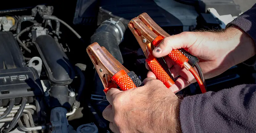 Holding jumper cables in front of a vehicle battery