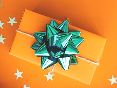 A gift wrapped in orange with a green bow