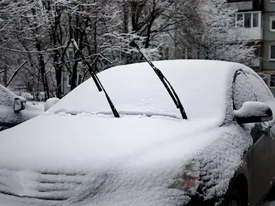 Car covered in snow with the wiper blades up