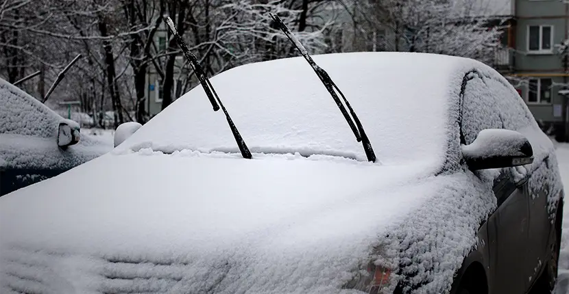 Car covered in snow with the wiper blades up