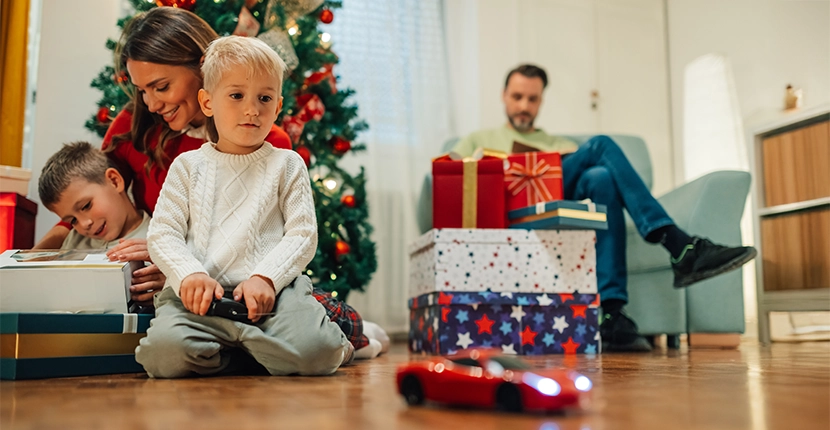 Child playing with a remote controlled vehicle with family in the background