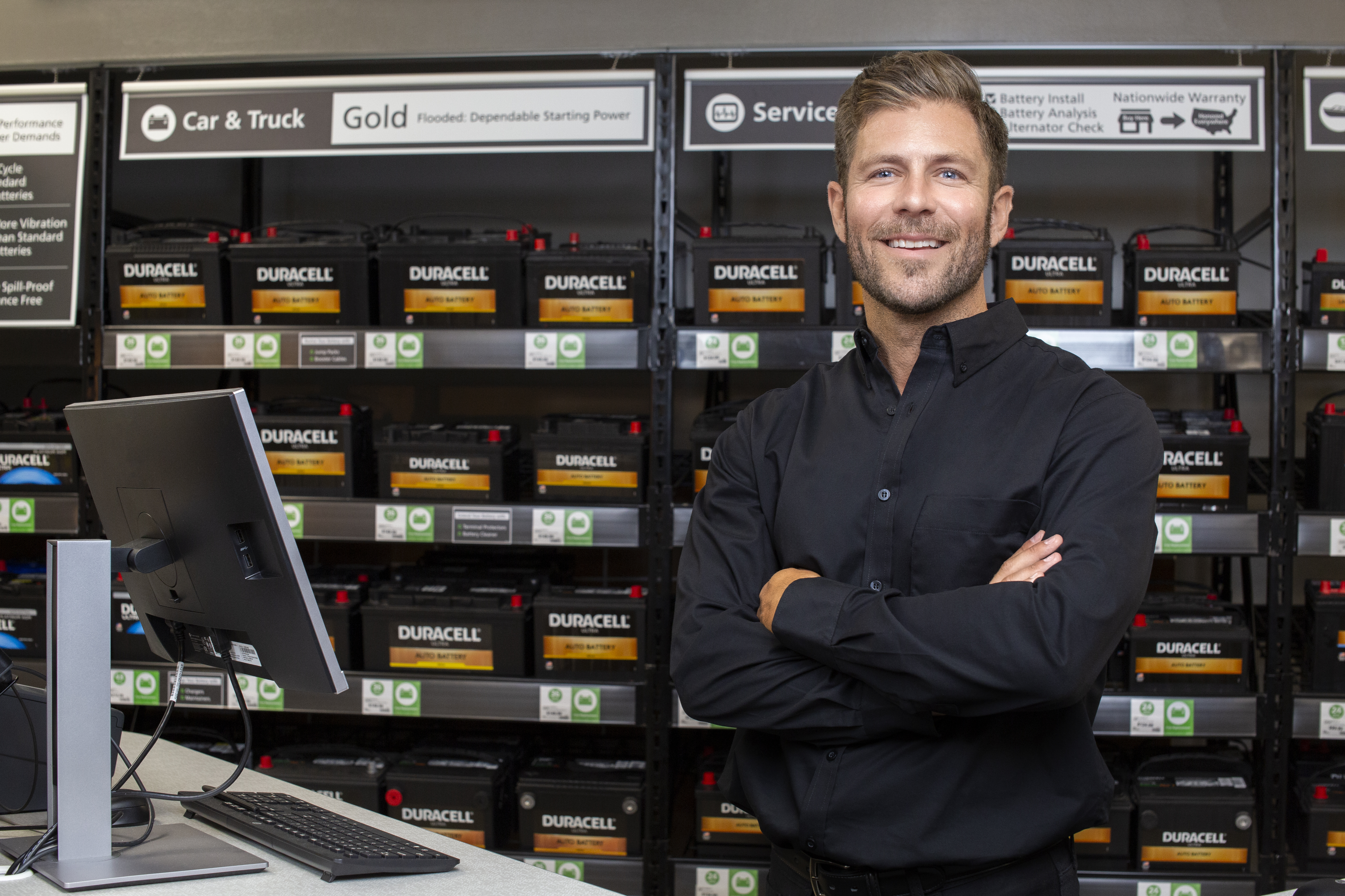 Franchise owner standing in front of the auto battery racks